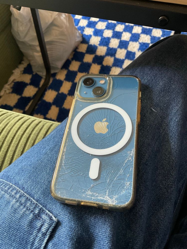 the back of an iphone covered in spiderweb cracks under the clear case. the case itself appears to be undamaged