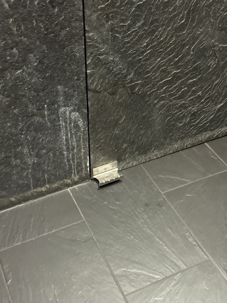 A photo of a bathroom door with a foot hold that you can use to open the door instead of having to touch the nasty door handle.