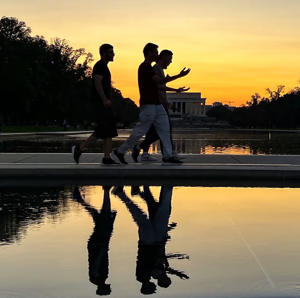 Three men walking along the National Mall in Washington, DC with the Lincoln Memorial in the background