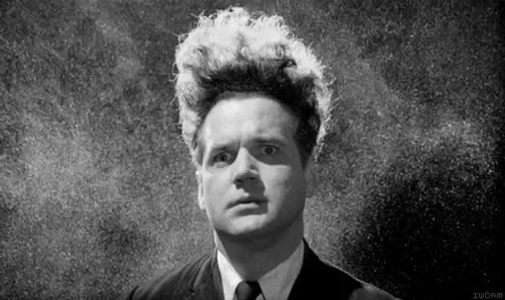 a black and white photo of a man in a suit and tie with white hair