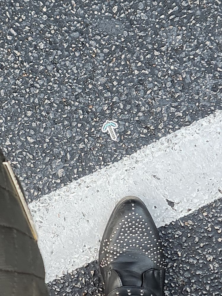 a minecraft diamond pickaxe sticker on the ground next to my black boot