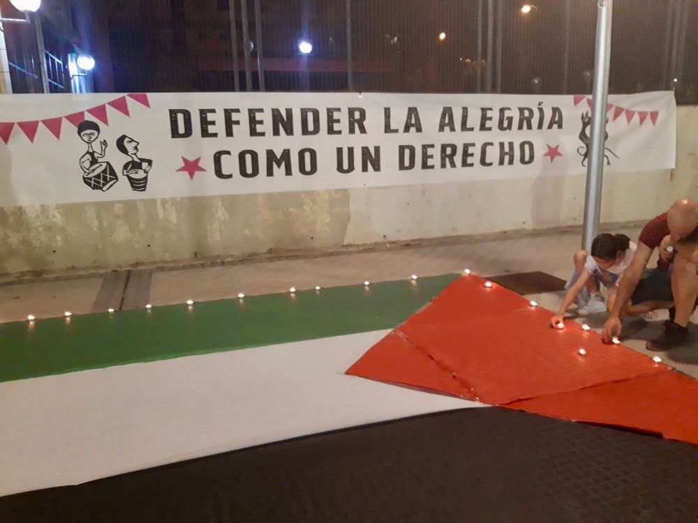 Pancarta que lee “Defender la alegría como un derecho”, junto a la bandera de Palestina. 