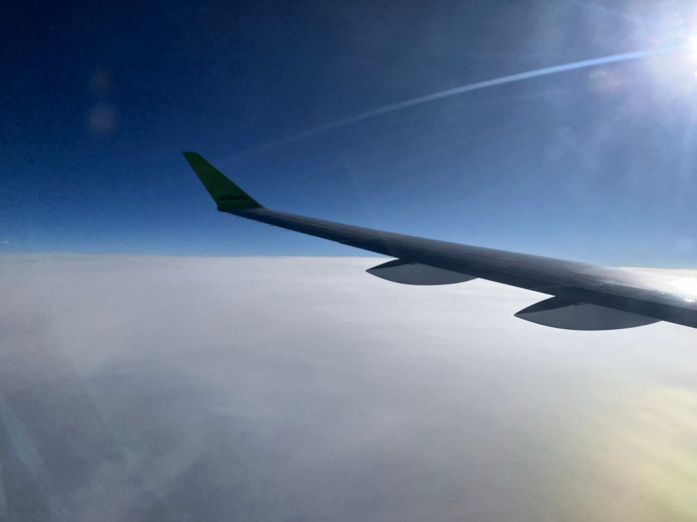 An aircraft wing above a bank of clouds.