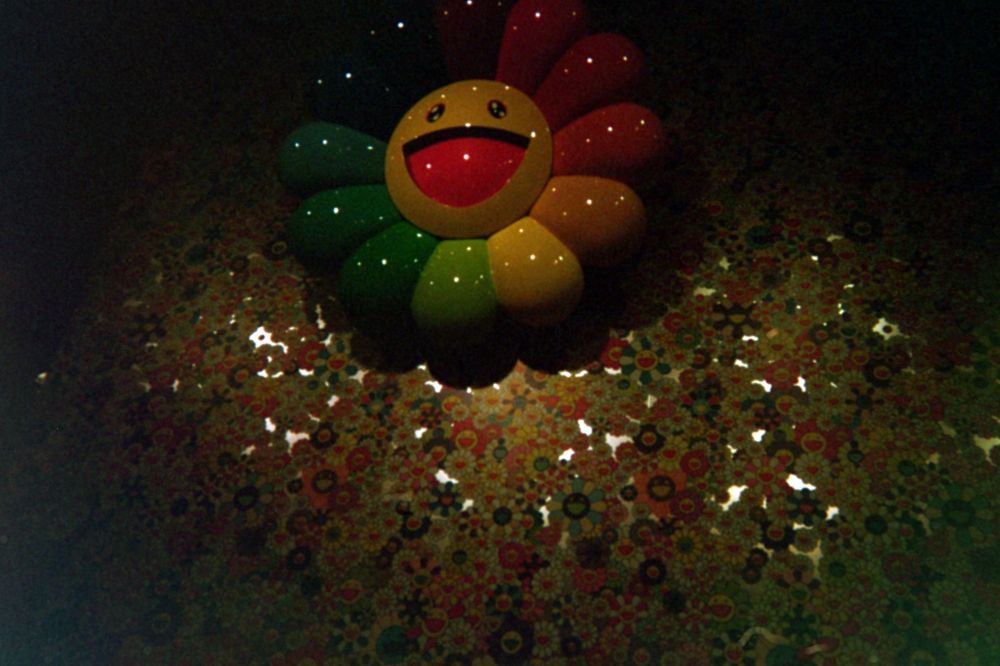 that big iconic rainbow flower with a face mounted high on a wall with his flower pattern on it