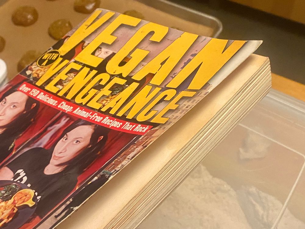 Photo of the cover of a heavily used copy of Vegan With A Vengeance by Isa Chandra Moskowitz.