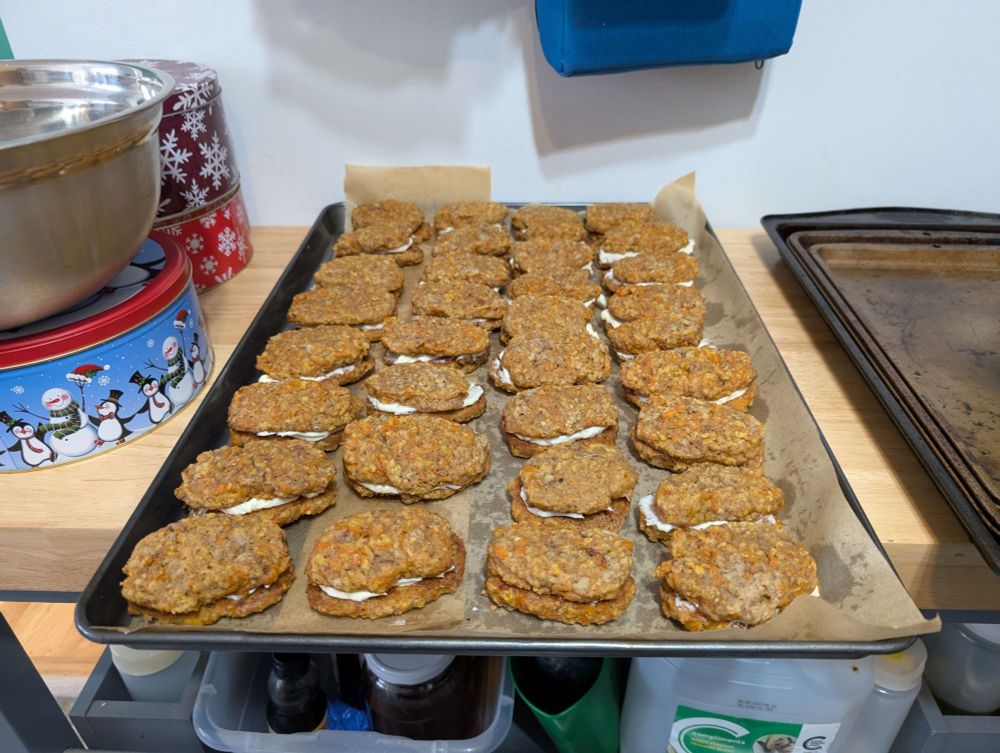 A tray of completed carrot cake cookies, with cream cheese filling between two cookies.
