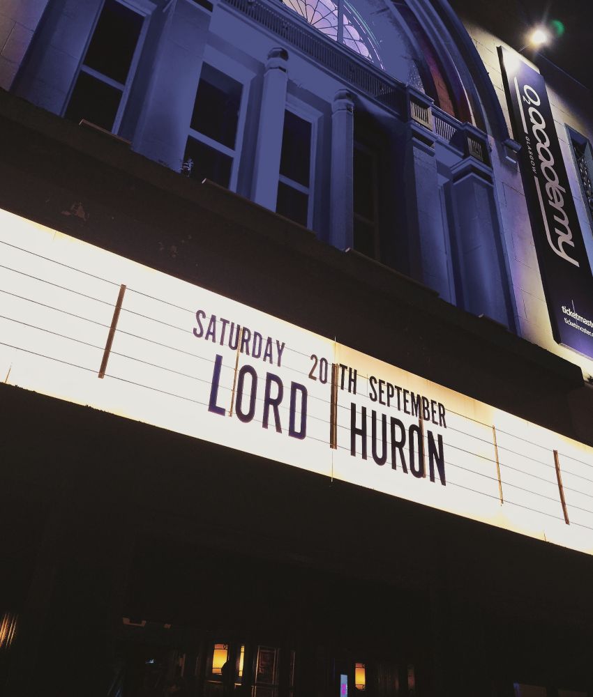 The outside of the gorgeous Academy in Glasgow, the venue for tonight's gig. "Lord Huron" is displayed in lights, while the historic building is illuminated in blue.