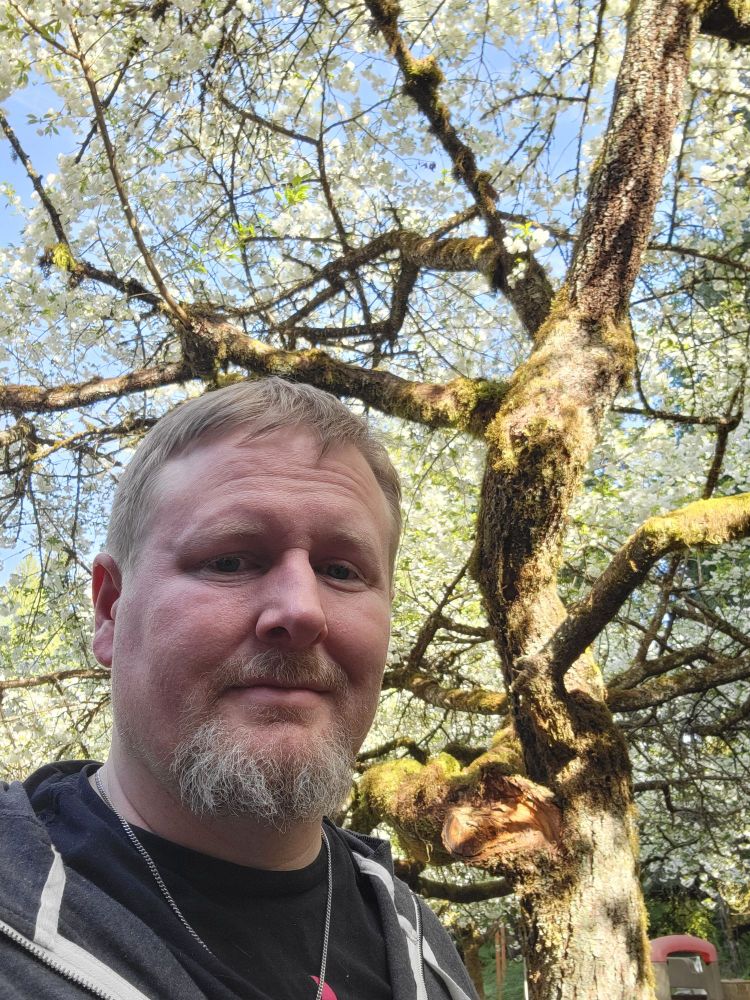 Ryan in front of a tree covered in White cherry blossoms 