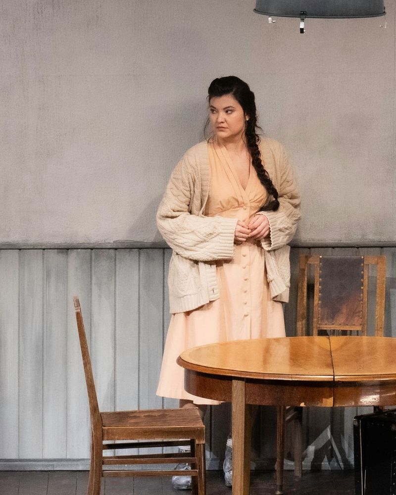 Aigul Akhmetshina als Adalgisa steht vor einem Tisch auf einer  Bühne
