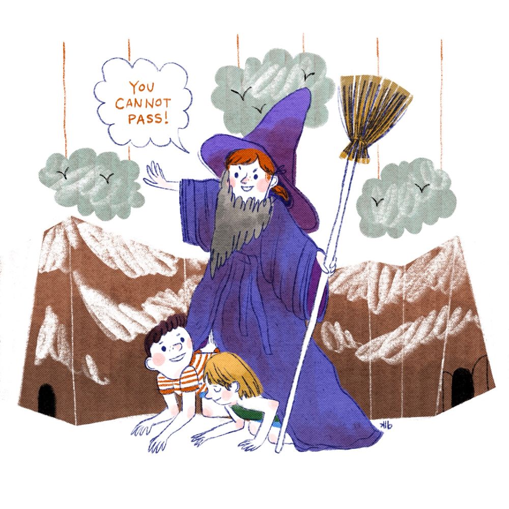 Three kids pretending to be Gandalf from LOTR. One stands on the other two’s backs in order to be taller - they wear a beard, hat and bathrobe and are holding a broom as a staff. Behind the kids, a cardboard mountain scene is portrayed. 