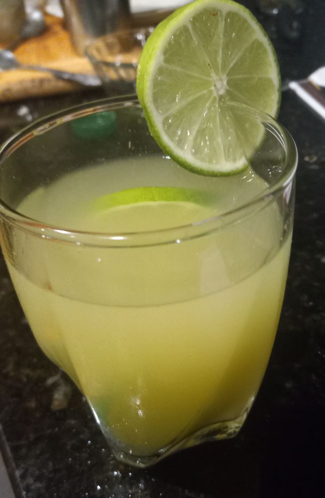 glass of a cloudy green liquid garnished with lime slices