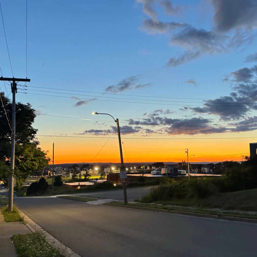 An urban St. Above a town and Sportsfield with a blue sky fading to brilliant yellow sunset glow 