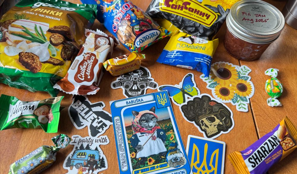 A pile of Ukrainian treats and sweets and an assortment of stickers notably a NAFO COCHET DIVISION BABUSKA card