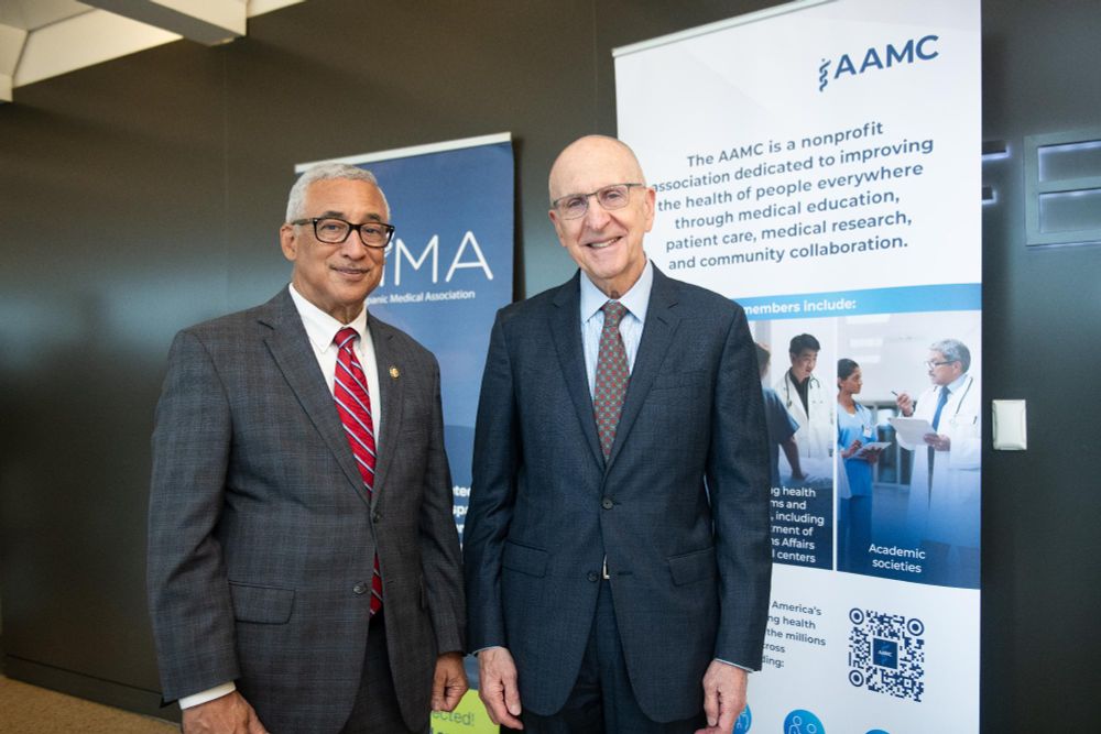 Two individuals posing at an AAMC (Association of American Medical Colleges) event, standing beside a banner that highlights AAMC's commitment to improving the health of people everywhere.