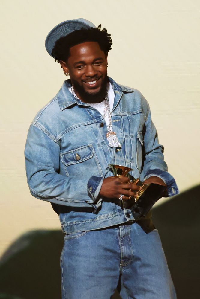 Kdot in a Canadian tuxedo smiling and holding one of his Grammys for ‘Not Like Us’