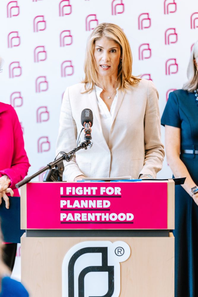 Congresswoman Lori Trahan standing behind a podium and microphone titled "I FIGHT FOR PLANNED PARENTHOOD"