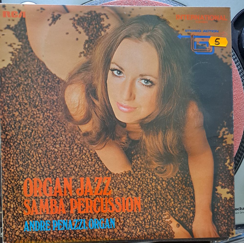 Record sleeve for Organ Jazz Samba Percussion by Andre Penazzi. A naked woman is lying down in a pile of coffee beans, her faced turned up to the camera with a slight edge of 'Do I REALLY have to do this?'
