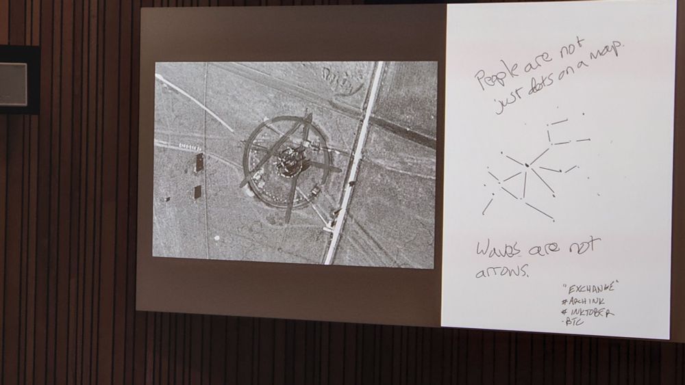 A coloour photo from a short presentation on behalf of the Black Trowel Collective on Saturday. It shows an early vertical aerial photo of Stonehenge, with a large A superimposed over the earthwork circle to create the familiar anarchist symbol. On the right is an image bearing startements such as "People are not just dots on a map".