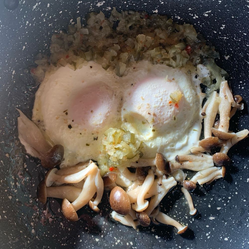 朝ごはんの目玉焼き。しめじとピクルスも入っていて、だまし絵のような顔になっています。