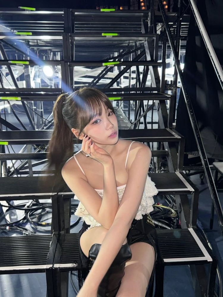 chaewon of le sserafim sitting on steps backstage