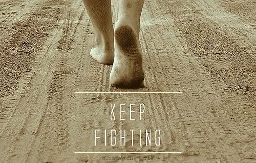 Barefoot woman walking on a dirt road with message, “keep fighting”