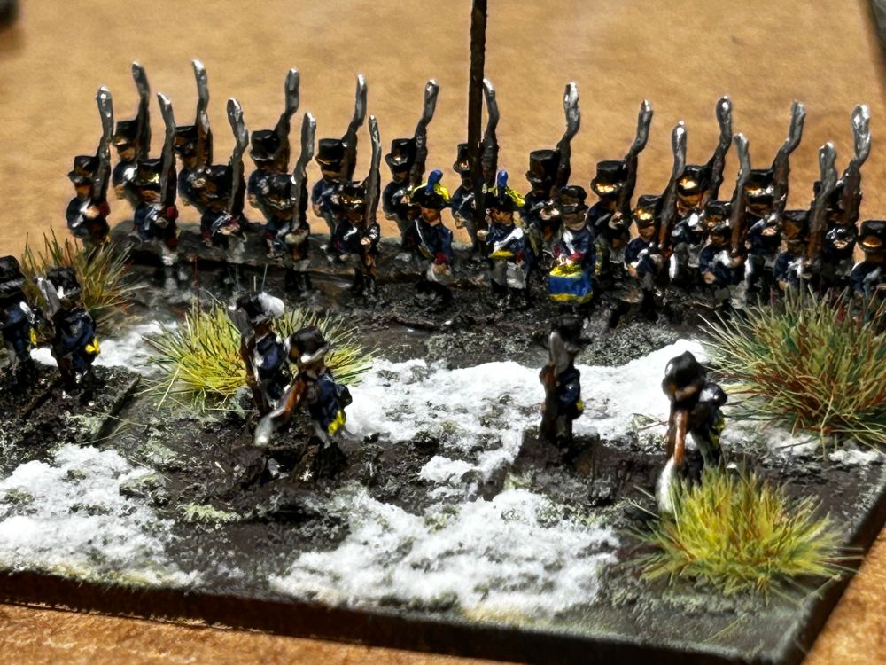 2 rows of miniature Swedish soldiers from the Napoleonic era, skirmishers deployed in front. Snow lies on the ground