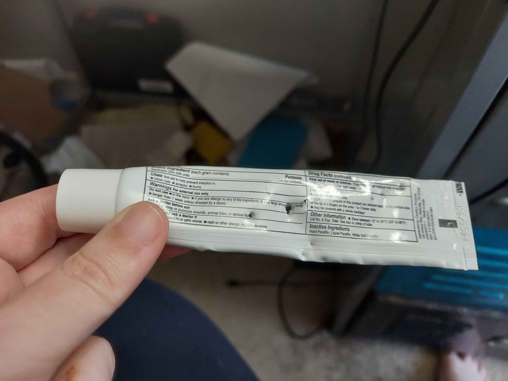 A tube of antibiotic ointment with several large fang punctures in it.  