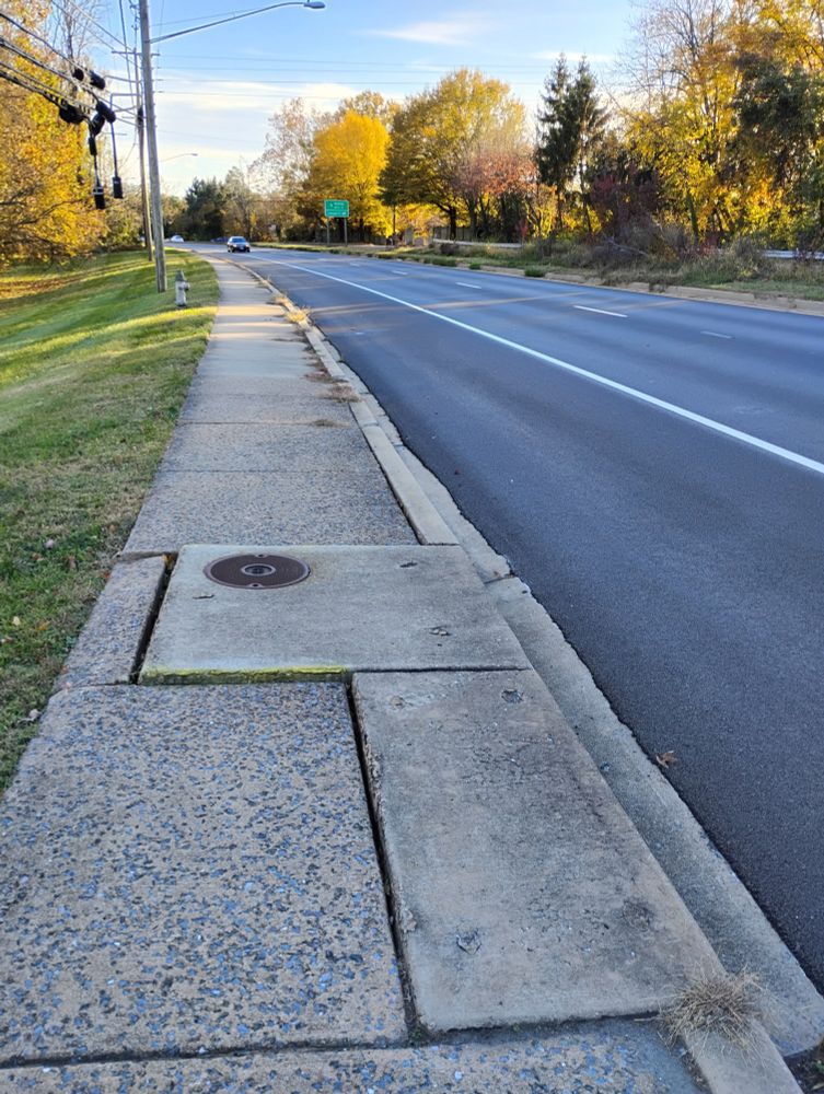 The sidewalk is uneven, causing an obstruction for wheelchair users and cyclists. The uneven sidewalk is on the eastern side of New Hampshire Avenue, near the Shiloh Christian Fellowship Church, approximately halfway between Southview Avenue and Windridge Acres Court.