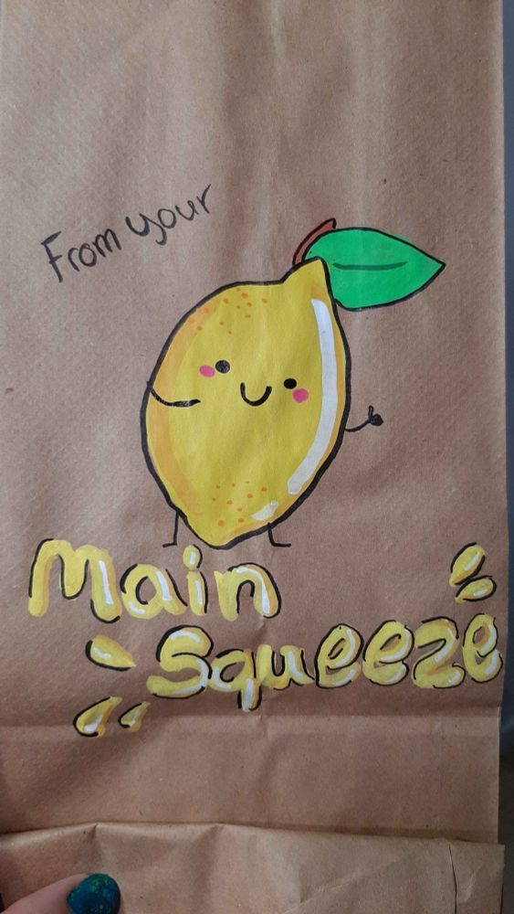 An acrylic marker illustration on a brown paper bag of a cheerful lemon saying "From your main squeeze" 