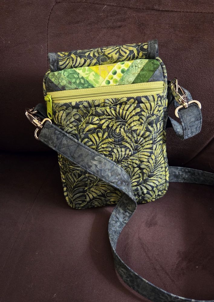 Back view of bag with zipper pocket and quilted band at top.  the front flap is attached at the back and wraps over the top.  It hasn't settled yet so it's puffing up in the air a little but it will relax in use.  
I was originally going to put the quilted strip at the top of the slip pocket but it worked perfectly as the top panel of the zipper pocket.