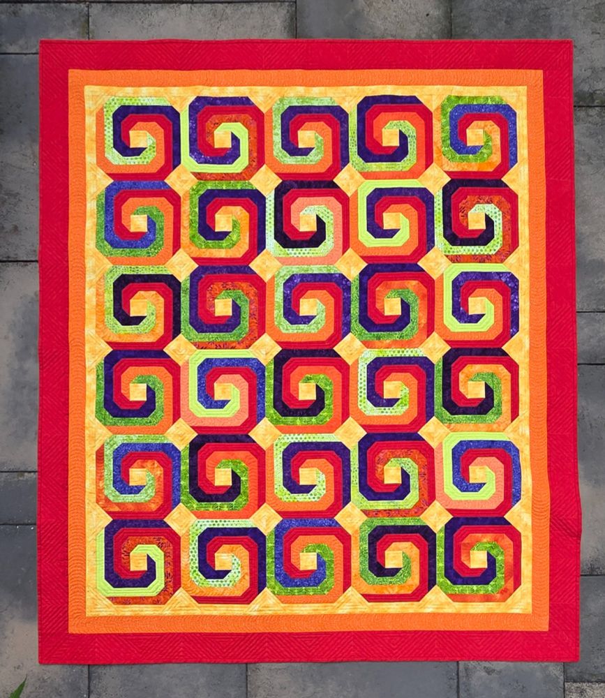 Red, orange, yellow, green, purple spiral quilt showing the whole pattern.