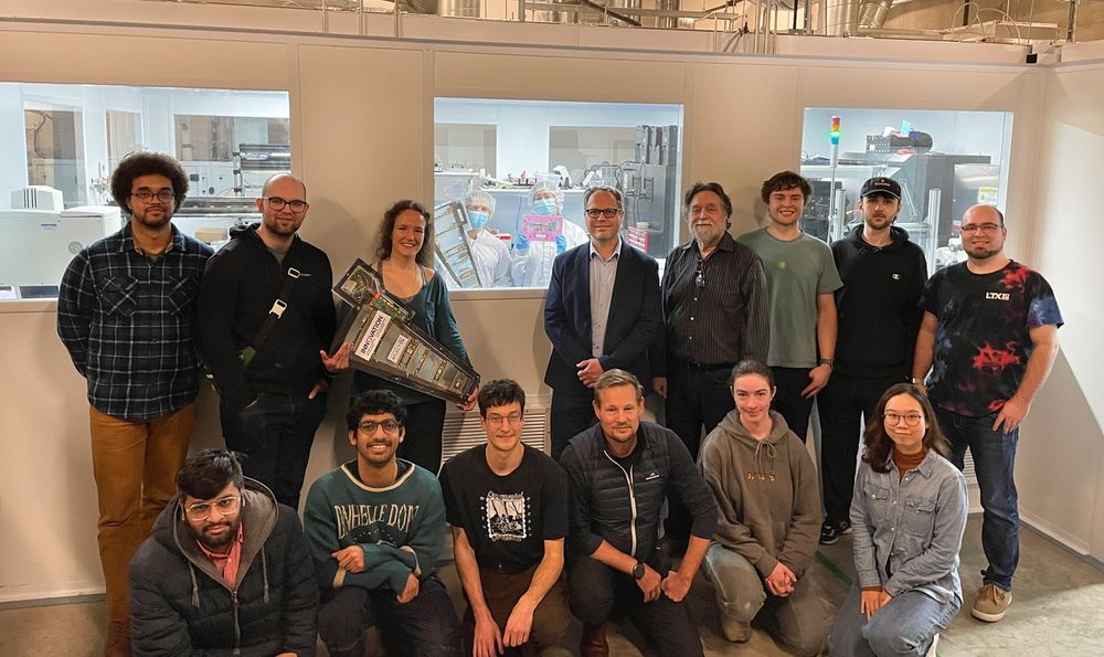 The research team poses for a group photo outside of a clean room where they are fabricating parts for CERN's Large Hadron Collider.