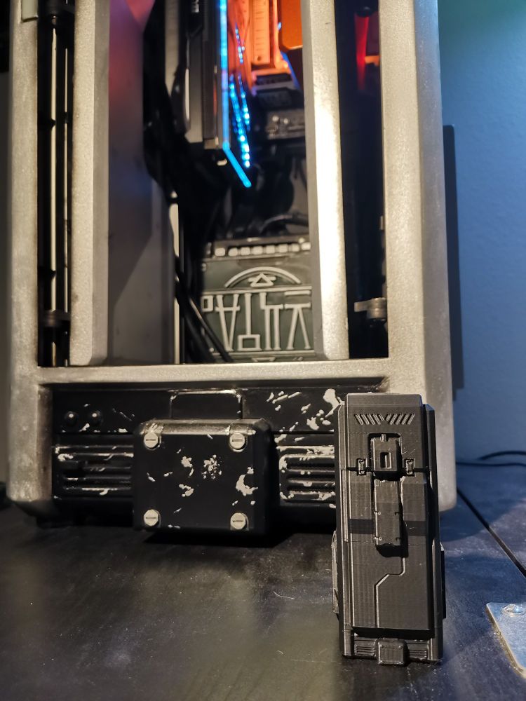 A photo of a 3d printed miniature corpus locker from the game warframe in front of a much larger corpus locker pc