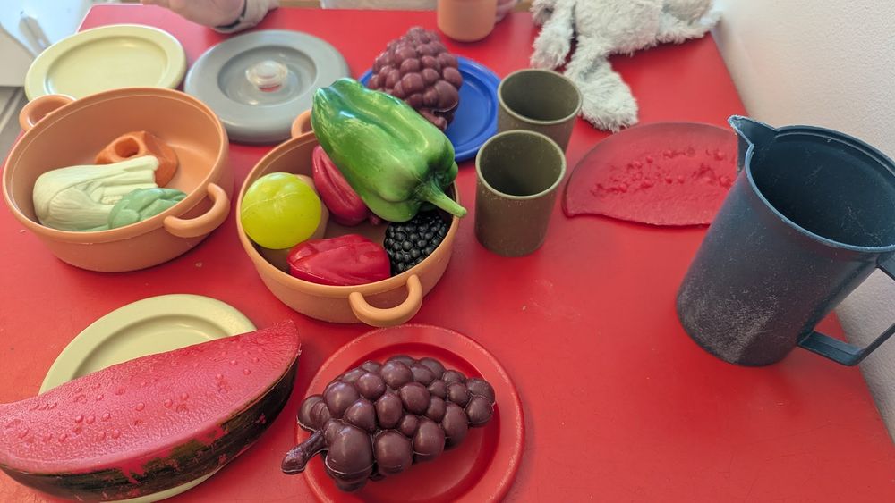 A table setting made entirely of toy food and dinnerware for toddlers.