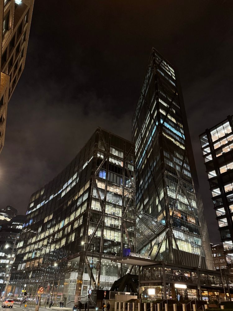 Tall buildings with curves and angles and multiple illuminated floors against a dark sky backdrop. #London