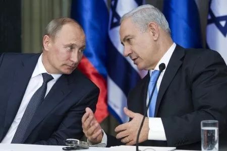 Vladimir Putin seated next to Benjamin Netanyahu in an animated conversation 