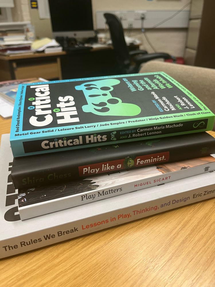 Stack of four books about gaming, from the bottom up: Eric Zimmerman’s The Rules We Break, Miguel Sicart’s Play Matters, Shira Chess’s Play Like a Feminist, and Carmen Maria Machado and J. Robert Lennon’s (eds.) Critical Hits.