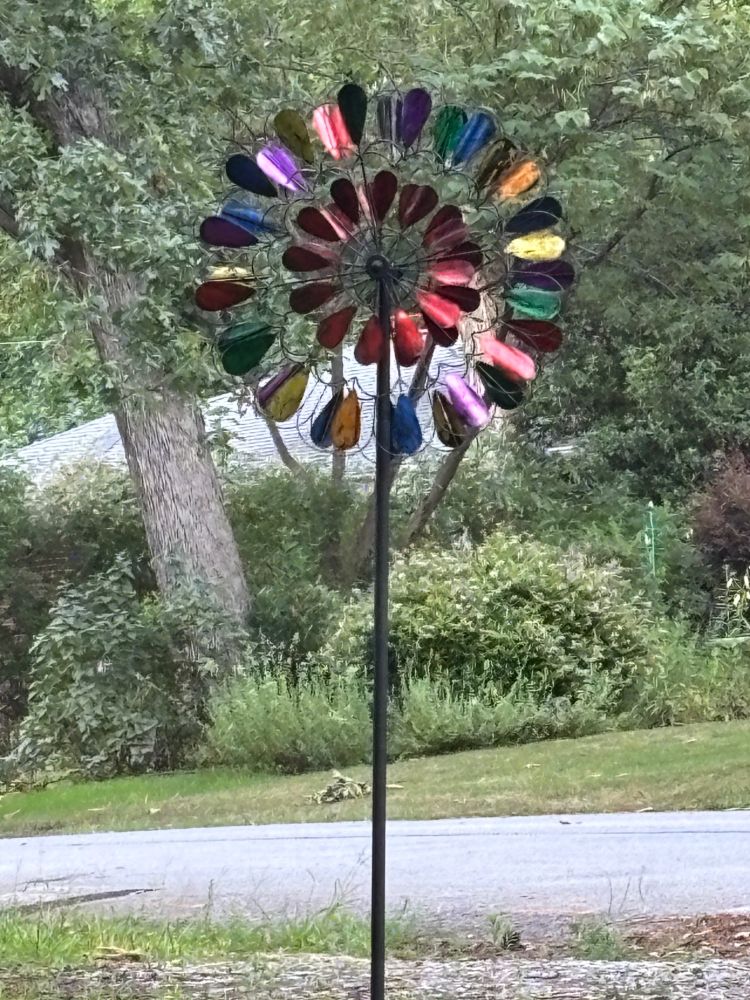 A large yard spinner with four movable circles that will spin in the wind.   It is shaped something like a zinnia flower. the two inner circles red "petals" and the two outer circles have petals of different colors (yellow, purple, pink. green blue)