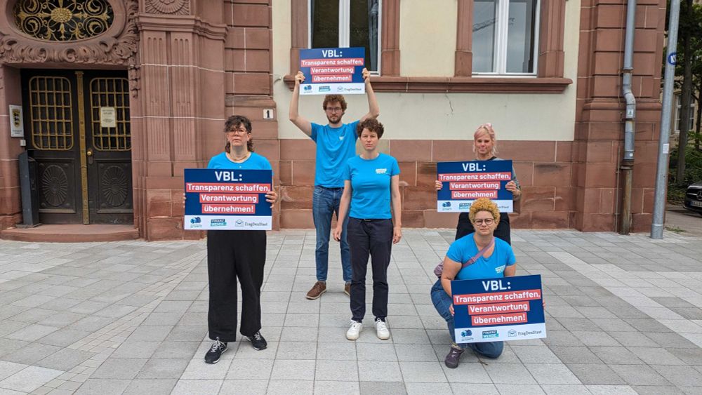Aktivist*innen stehen mit Schildern vor dem Verwaltungsgericht Karlsruhe. Darauf steht: "VBL: Transparenz schaffen, Verantwortung übernehmen!"
