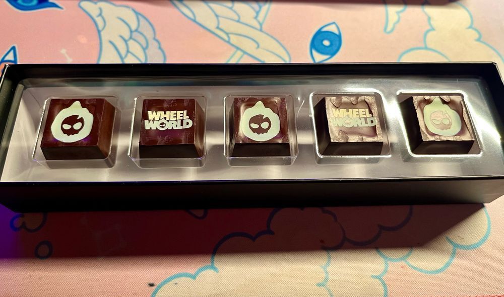 an open box of chocolates. they have been customized with the wheel world logos on them. 