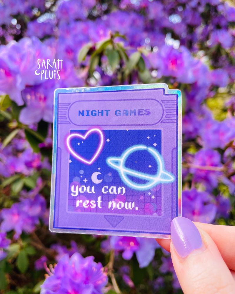 Eine Hand hält einen Sticker mit Videospielmotiv.