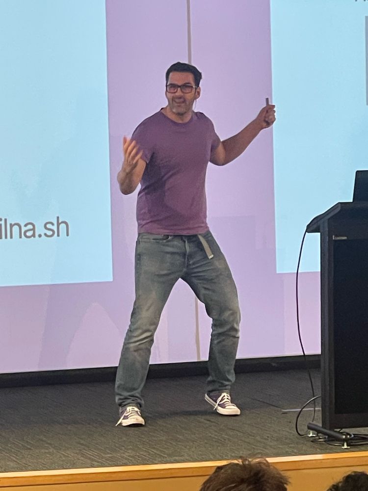 Phil Nash on stage at Web Directions in matching purple shoes shirt and slides!  