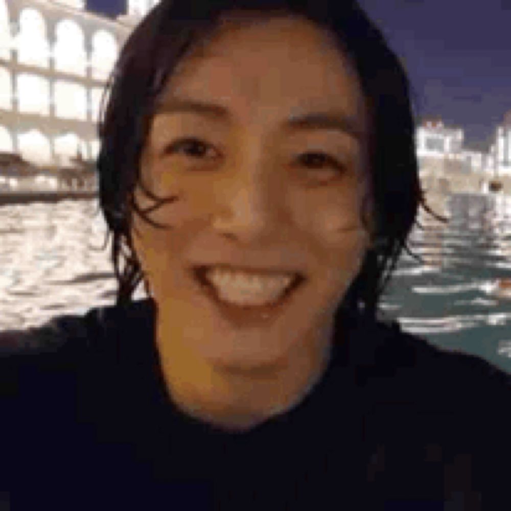 a close up of a person 's face smiling in front of a body of water at night .