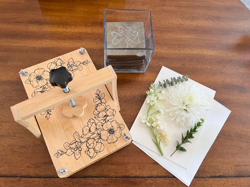 An overhead view of a flower press next to some flowers on blotting paper. 