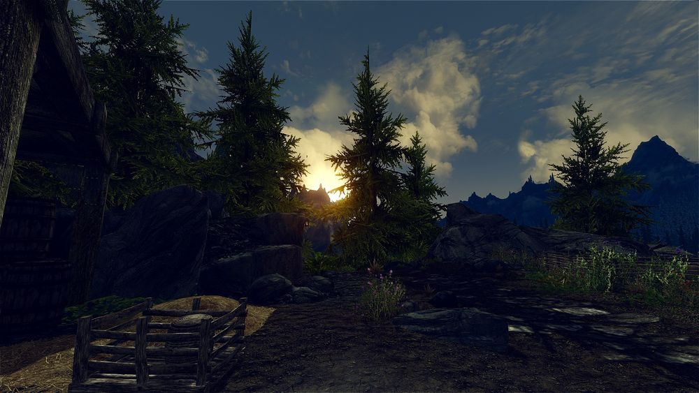 Modded Skyrim screenshot, looking east from Katla's Farm in Haafingar.  The sun rises between the trees, silhouetting the mountains and Solitude's Blue Palace.