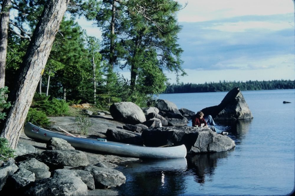 Ned Johnston in a very Marlboro Country-esque pose on a rock near his canoe. Early 1980s, northern MN lake.