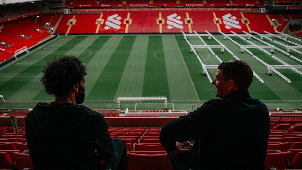 Mo Salah and Steven Gerrard sit together looking over Anfield.