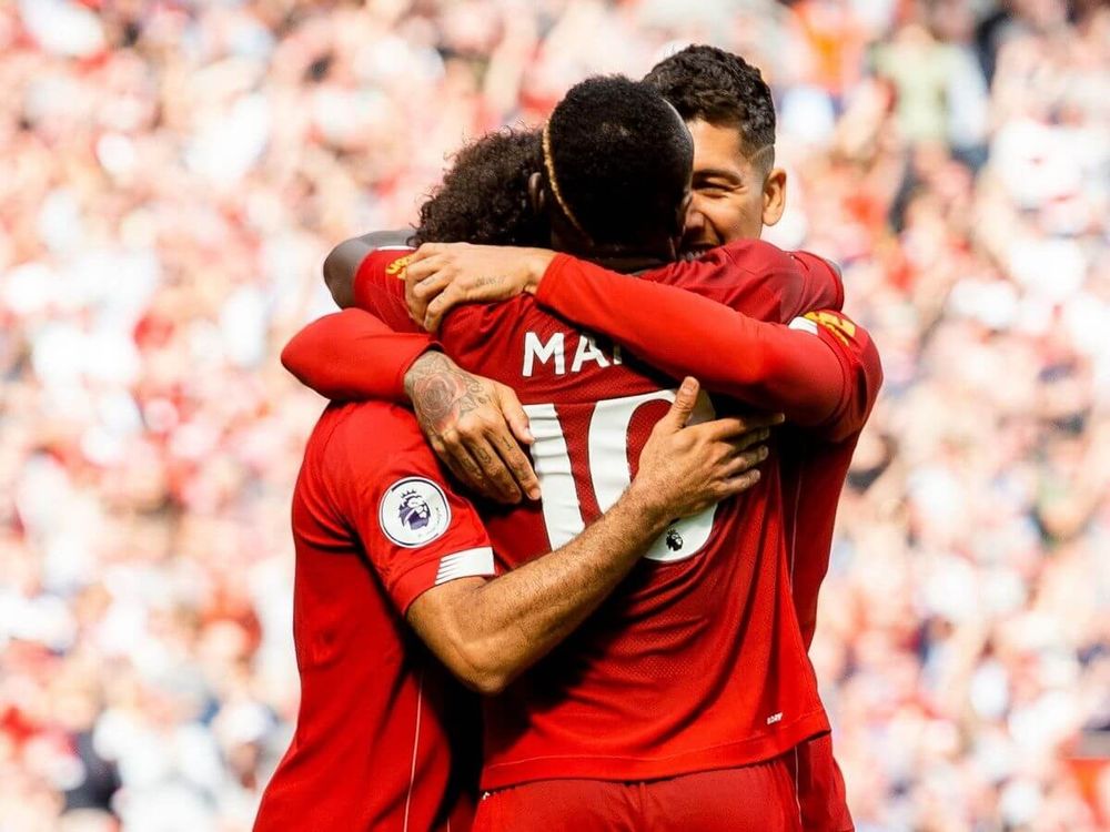 Sadio Mané and Roberto Firmino embrace Mo Salah in a Premier League game for Liverpool.