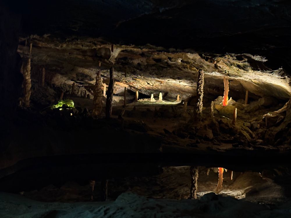 Das Foto zeigt das Innere einer Höhle, in der einzelne Stalagmiten und Stalaktiten beleuchtet sind. 