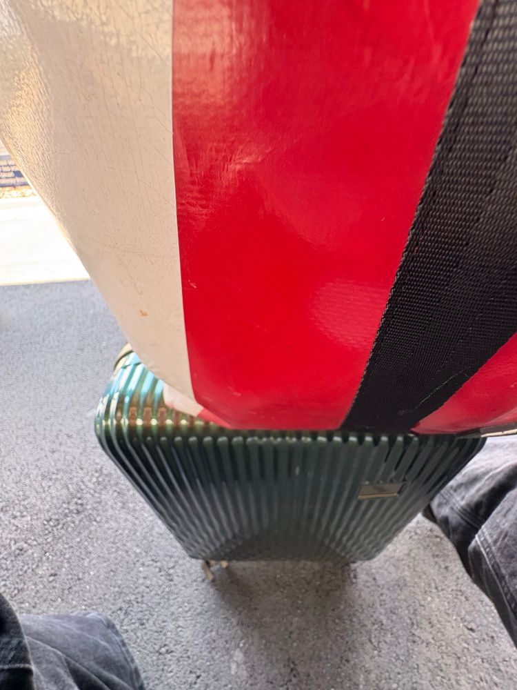 Fussboden, meine Beine (angeschnitten), ein kleiner Rollkoffer und obendrauf mein Rucksack. 